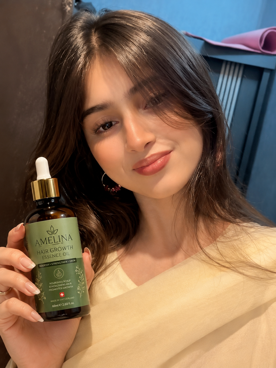 Happy AMELINA customer holding the Hair Growth Essence Oil bottle